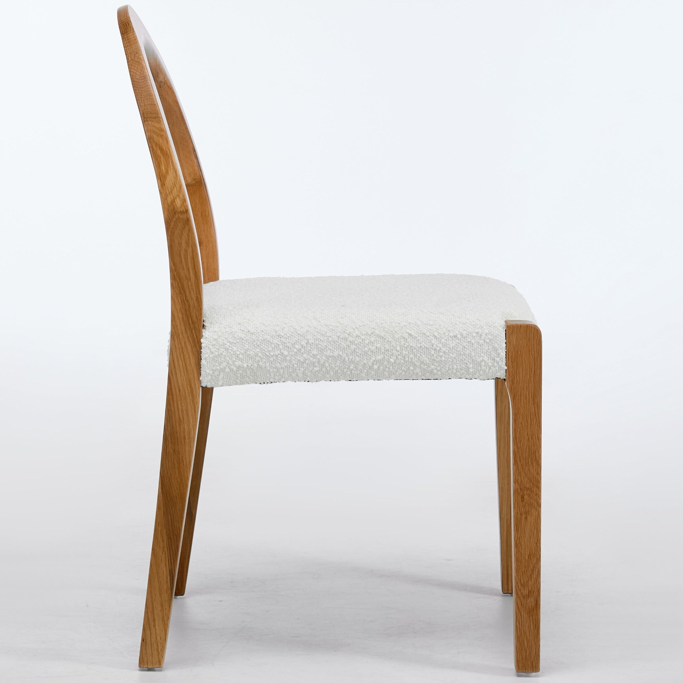 Wooden chair with a white cushioned seat on a light gray background