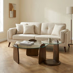 Beige sectional sofa in a living room with glass coffee table and decorative items.
